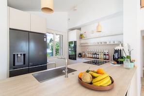 A modern kitchen with a built-in refrigerator, a coffee station, and a fruit bowl on the counter. - Frontignan, Villa Bianca, pool and garden (Frontignan)