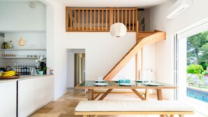 A modern kitchen with a dining area, a staircase, and a view of a swimming pool.