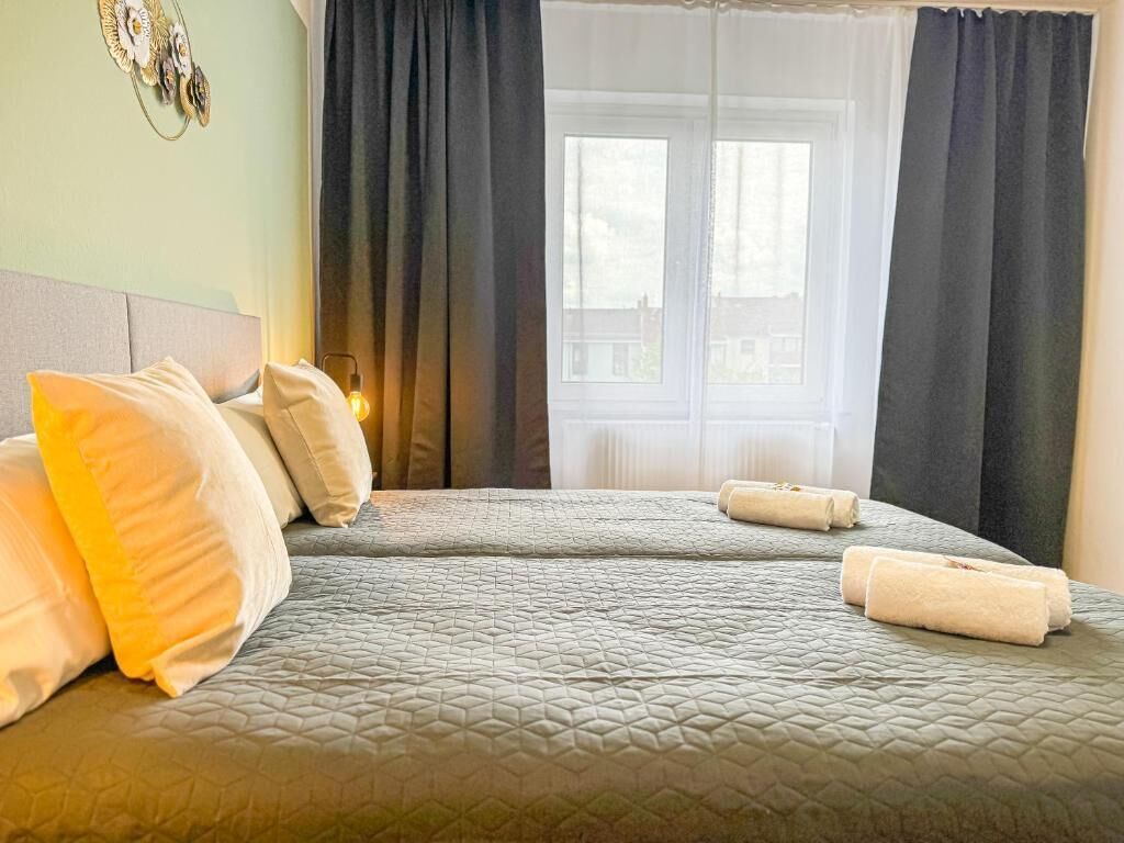 Ein Hotelzimmer mit Bett, Kissen, einem Fenster mit Vorhängen und einer Wanddekoration.