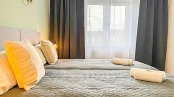 Ein Hotelzimmer mit Bett, Kissen, einem Fenster mit Vorhängen und einer Wanddekoration.