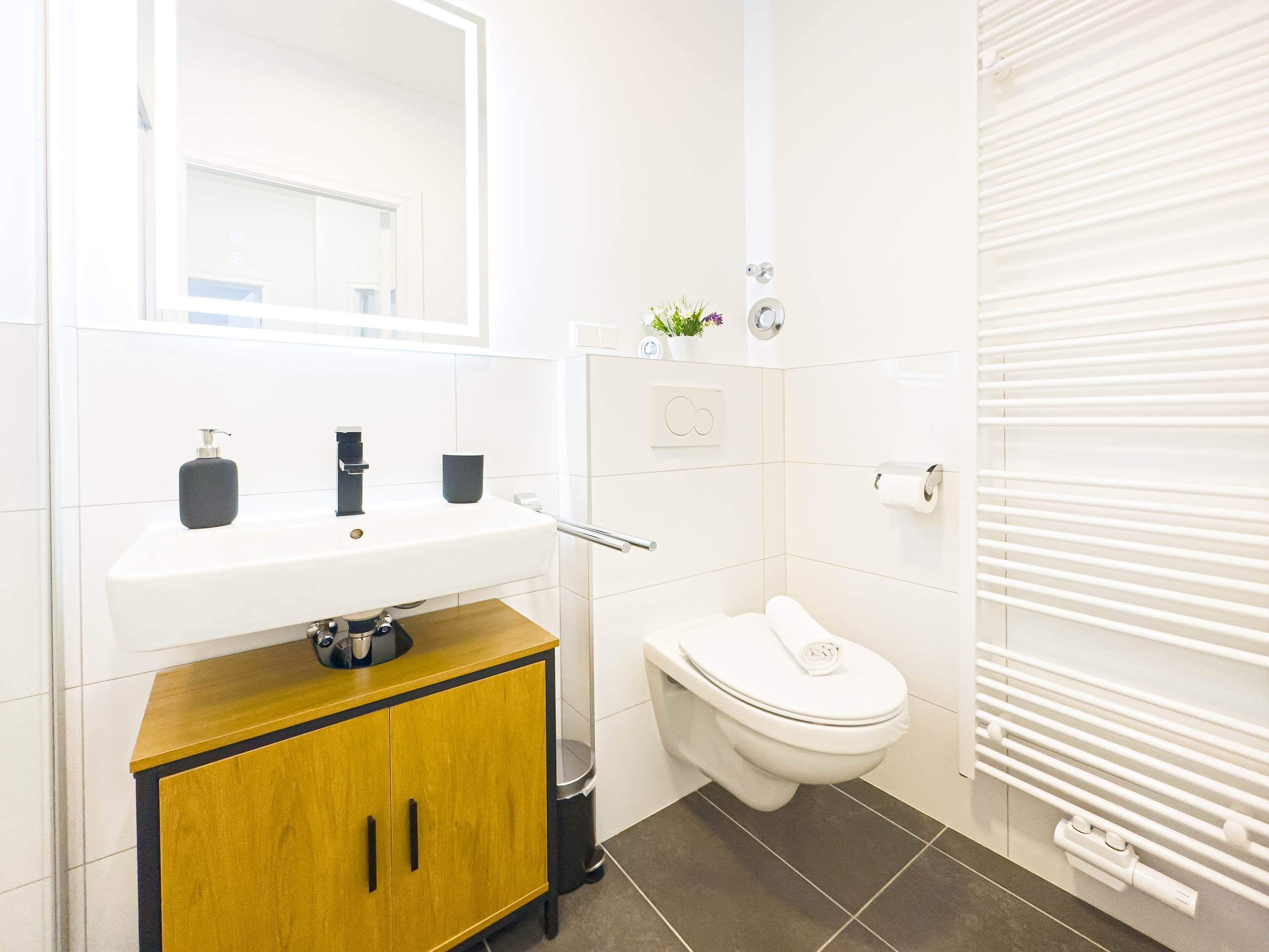 A modern bathroom with a white sink, a toilet, and a shower area.