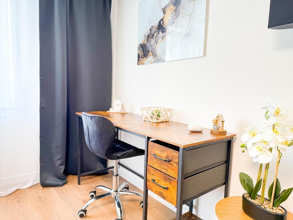 Un bureau moderne, avec une chaise, une petite plante en pot et une œuvre d’art encadrée accrochée au mur.