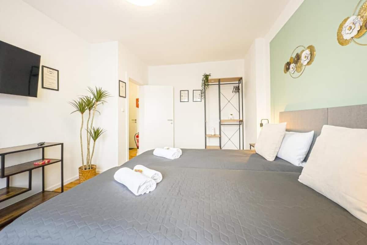 Hotellihuone, jossa on suuri sänky, työpöytä, televisio ja ovi, joka johtaa kylpyhuoneeseen.