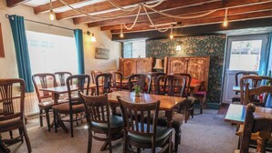 A dining area with wooden tables and chairs, a patterned wall, and a rope ceiling. - Upstairs at the Sun Inn (Mold)