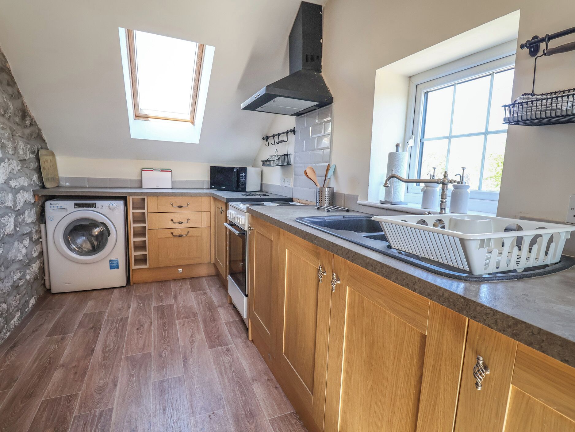 A kitchen with a washing machine, oven, and a window with a view.