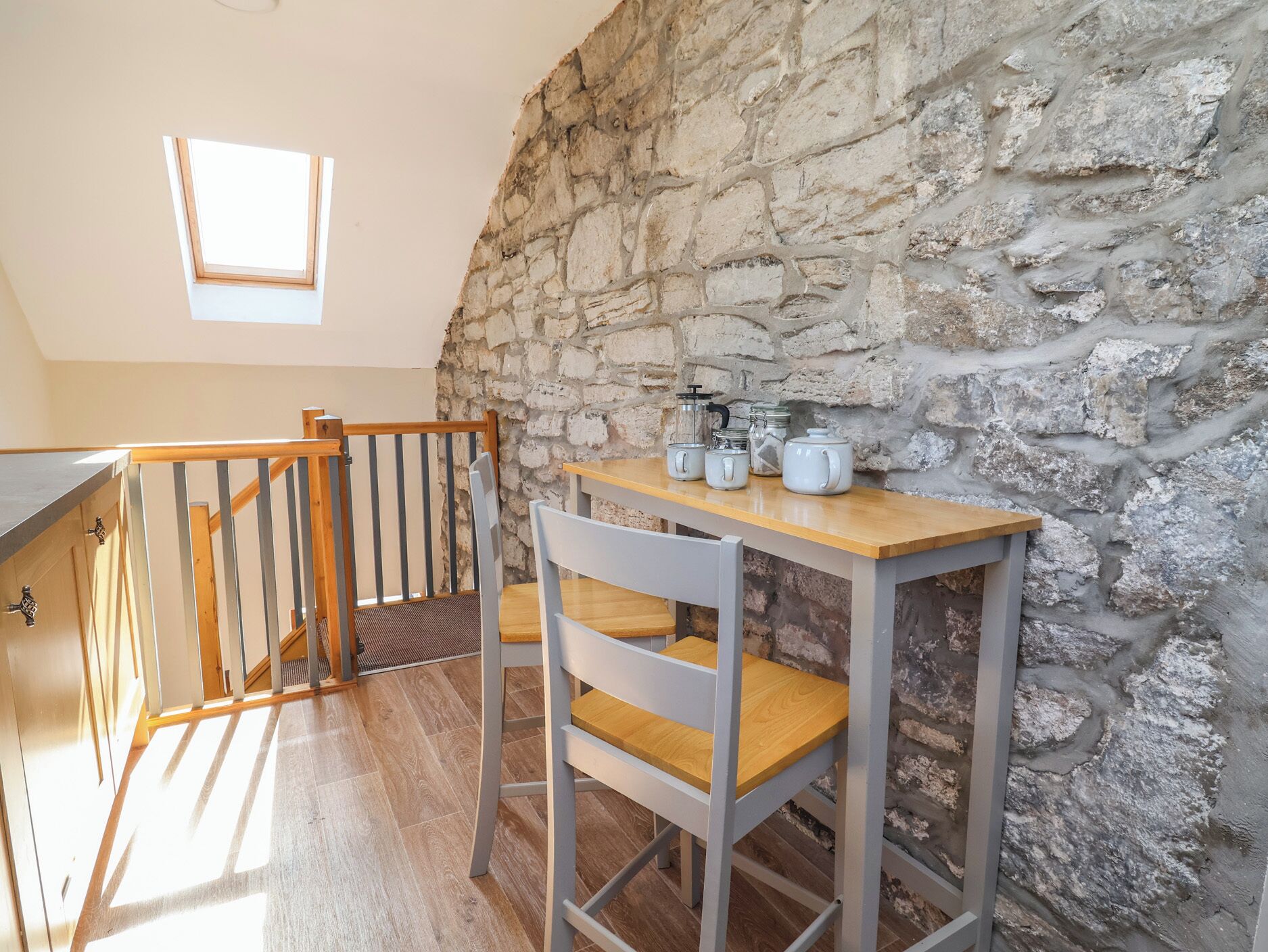 A kitchen with a stone wall, a wooden table, and a chair.
