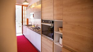 Een moderne keuken met houten kasten, een inbouwoven en een rood tapijt.
