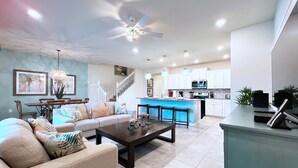 A modern living room with a sofa, coffee table, and dining area. - South-Facing Pool & Spa • Lazy River & Waterslides • Gated Resort • Near Disney (Davenport)