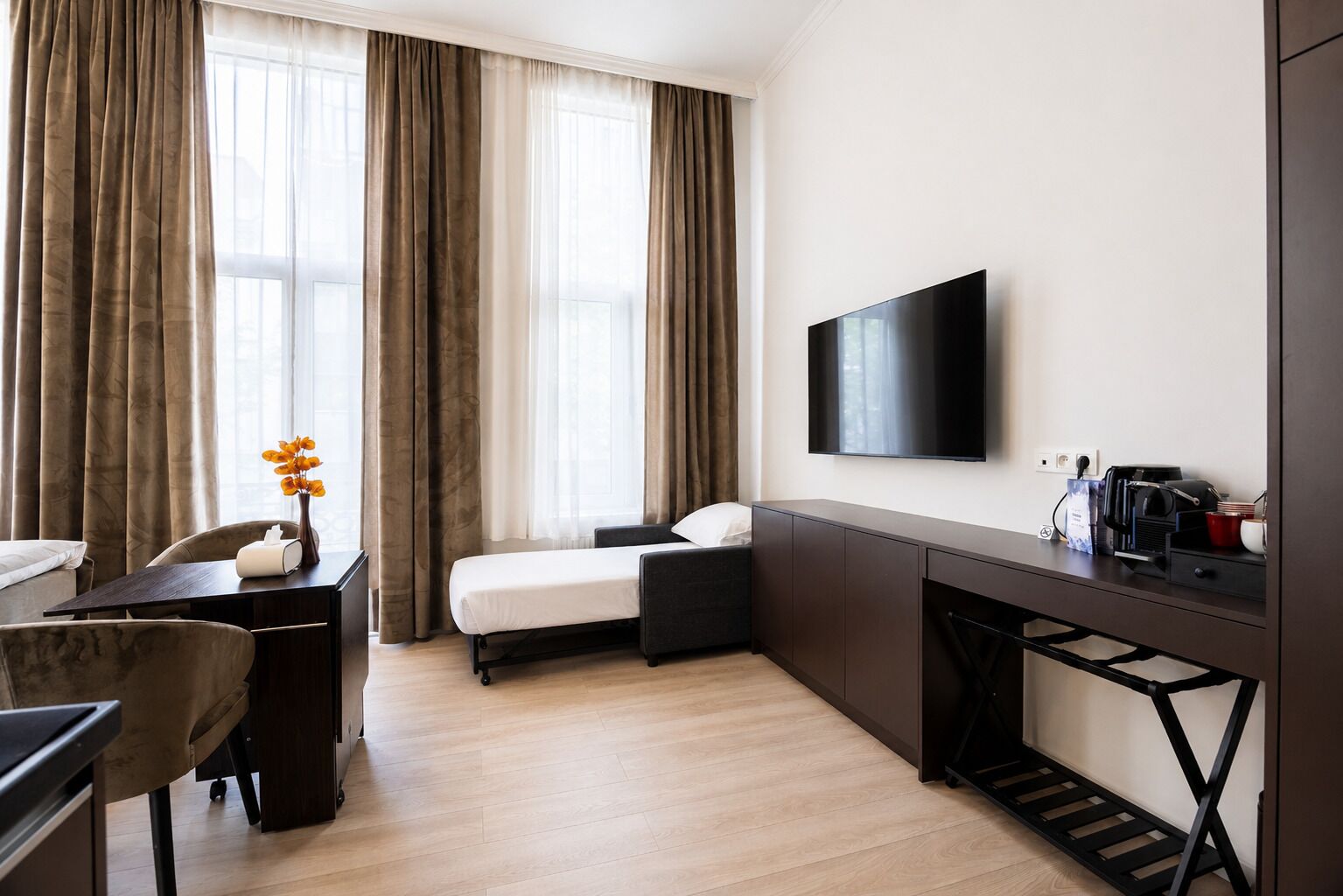 Een hotelkamer met een bed, een bureau, een stoel, een televisie en een koffiezetapparaat.