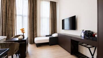 Een hotelkamer met een bed, een bureau, een stoel, een televisie en een koffiezetapparaat.