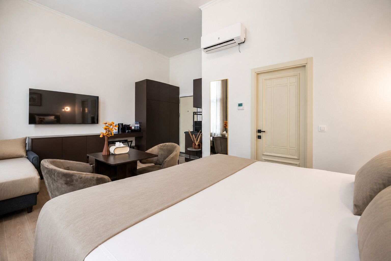 Ein Hotelzimmer mit Bett, Sofa, Schreibtisch und Kleiderschrank.