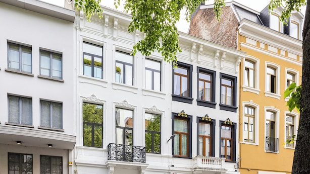 En række høje bygninger med traditionel europæisk arkitektur, udsmykkede vinduesrammer og altaner.