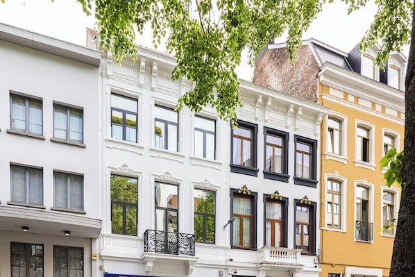 A row of multi-story buildings with traditional European architecture, featuring ornate window frames and balconies.