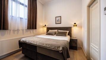 Una camera da letto con un letto grande, due comodini, un quadro appeso al muro e una finestra con tende.