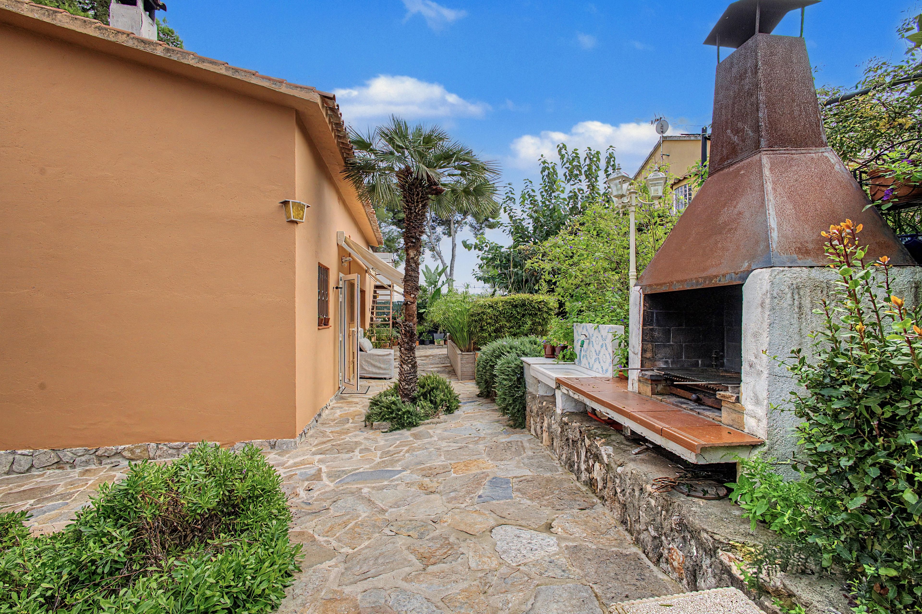 A stone pathway leading to a building with a barbecue area.