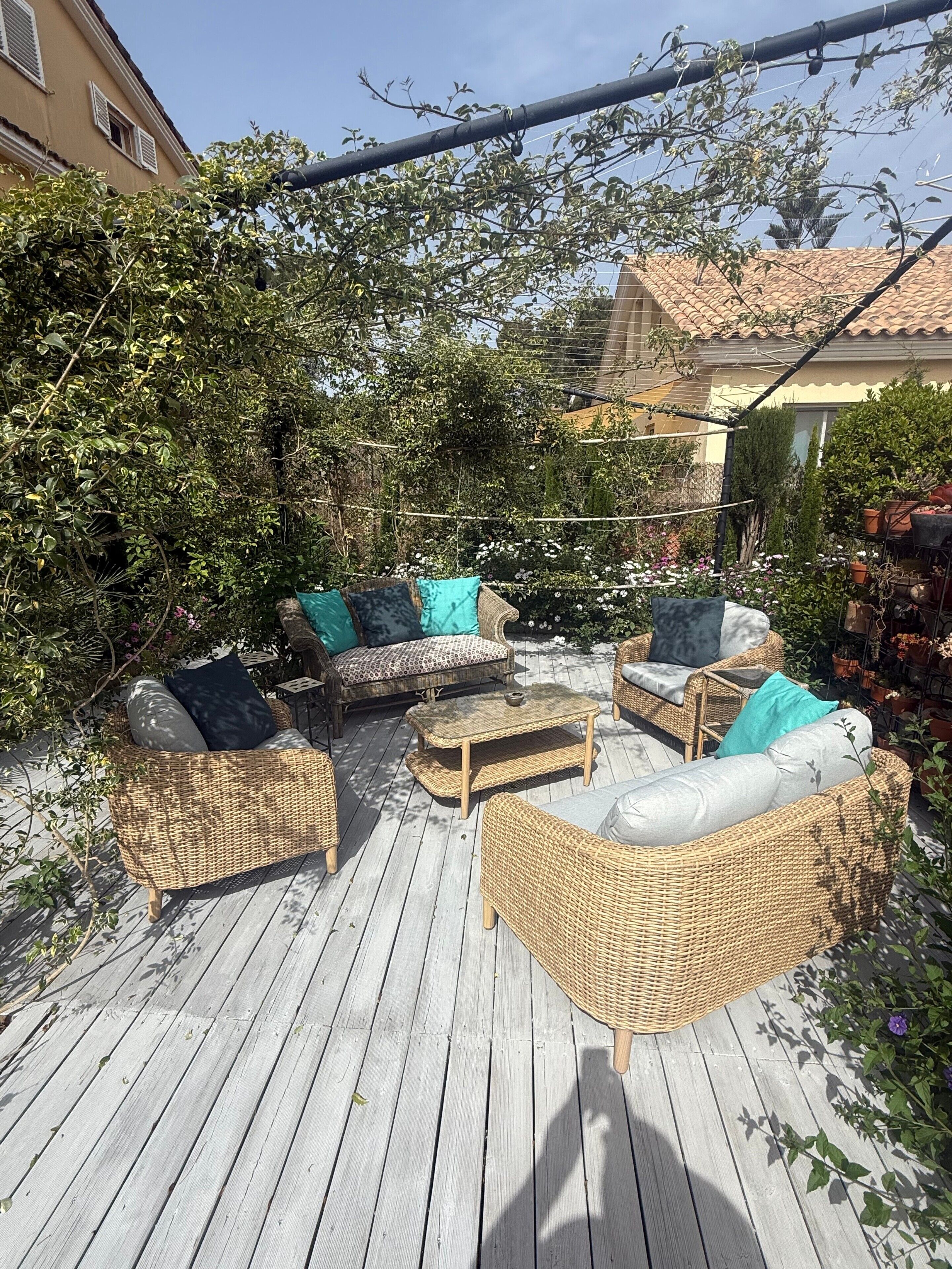 Un patio al aire libre con mobiliario de mimbre y una terraza de madera.