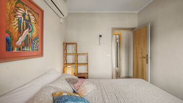 Une chambre à coucher avec un lit, une lampe suspendue, une étagère en bois et une porte.