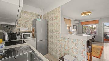 A compact kitchen with a refrigerator, microwave, and stove.