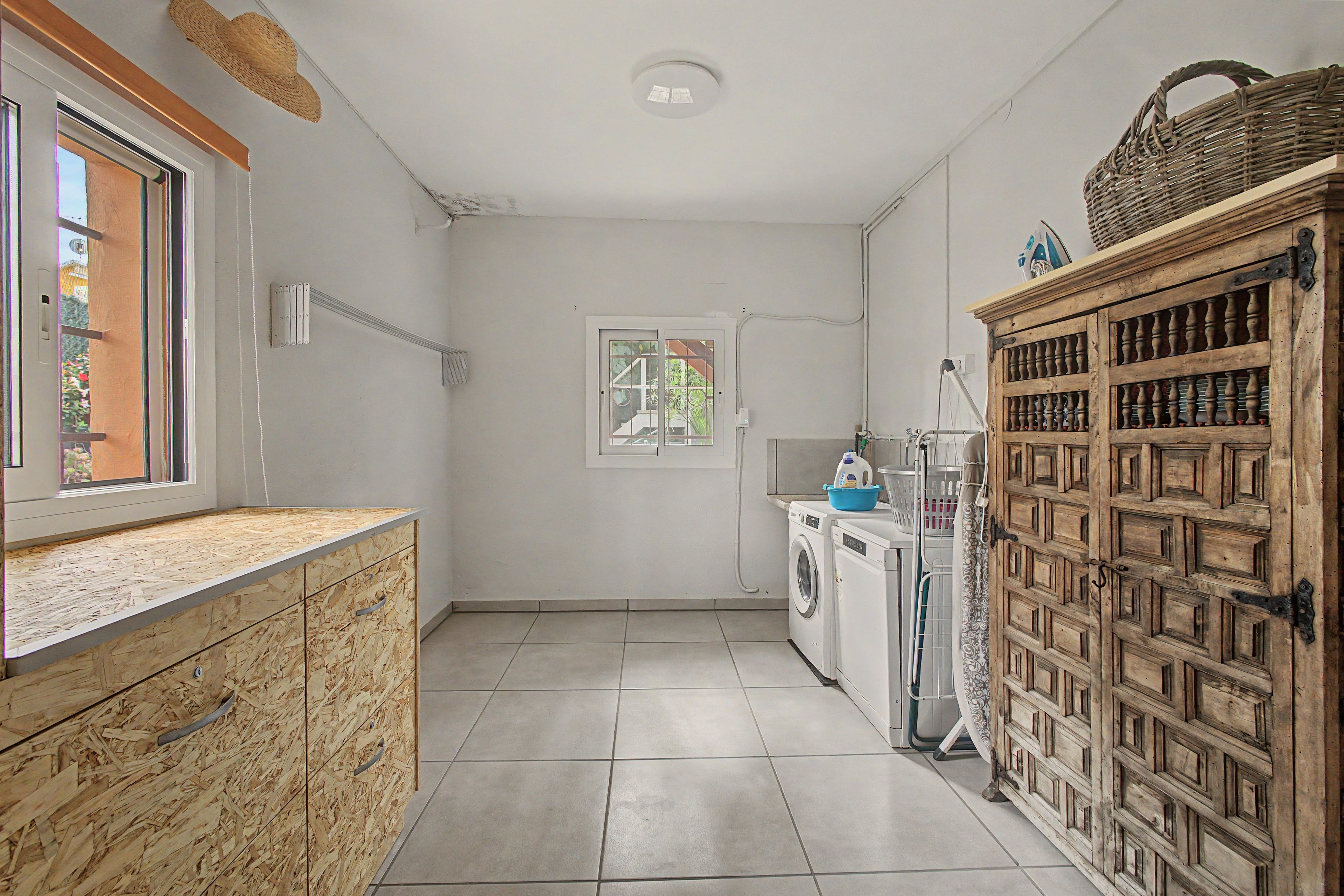 A laundry room with a washing machine, a dryer, and a wooden cabinet with shelves.