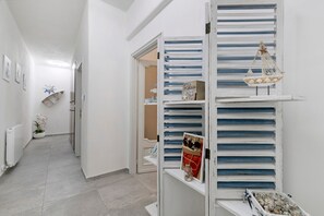 A hallway with a white door, a shelf with a decorative sailboat, and a potted orchid.