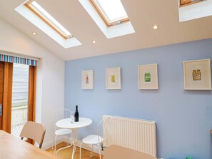 A room with a skylight, a table with chairs, a radiator, and framed pictures on the wall. - Peaslands (Sidmouth)