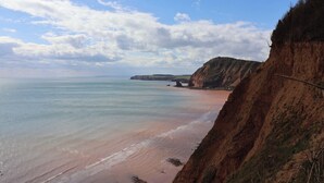 Eine Küstenlandschaft mit Klippen, einem Strand und wolkenlosem Himmel.