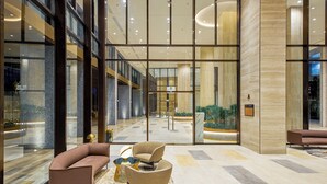A spacious lobby with a modern design, featuring a seating area with sofas and a coffee table, a reception desk, and a view of the interior through large glass doors. - Là Home - Stay Cozy, Stay Home Phú Mỹ Hưng (Ho Chi Minh City)