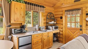 Una cocina compacta con armarios de madera, un microondas, un tostador y un lavamanos.