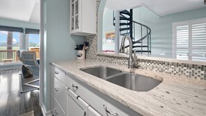 A modern kitchen with a large sink, white cabinets, and a view of the outdoors. - Spectacular Sunset Views, Quiet Location, Golf Cart Included, Private Deck - 7 Periwinkle Court (Fripp Island)
