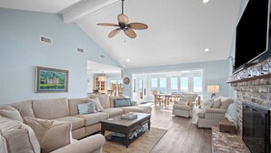 A spacious living room with a high ceiling, a fireplace, and a view of the outdoors. - Oceanfront, Private beach access, Golf Cart Included - 799 Marlin Drive (Fripp Island)
