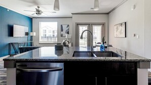 Een moderne keuken met een granieten aanrecht, een roestvrijstalen spoelbak en een plafondventilator.