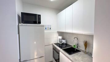 A compact kitchen with a refrigerator, microwave, coffee maker, and sink.