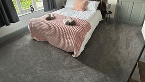 Ein Schlafzimmer mit Bett, Fenster, Tür und Blick ins Grüne.
