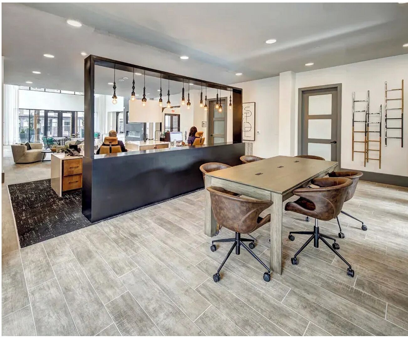 Un espace de bureau moderne doté d’une grande table de conférence, de chaises de bureau et de luminaires suspendus.