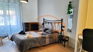 Un dormitorio con cama, escritorio, silla, cómoda y espejo.