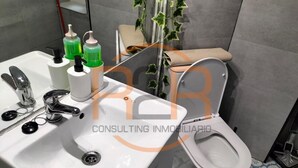 Un baño con lavamanos, grifo y retrete. Hay dispensadores de jabón en el lavamanos.