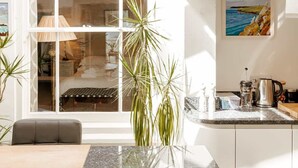 A modern kitchen with a large window, a hanging copper pendant light, and a view of the interior. - Chy En Glas - By Rowes Retreats (Falmouth)