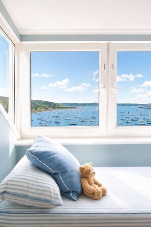 A bed with a view of a harbor through a window. - Chy En Glas - By Rowes Retreats (Falmouth)