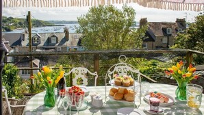 A table set for a meal with a view of buildings and greenery. - Chy En Glas - By Rowes Retreats (Falmouth)