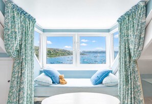 A bay window with a view of boats, a bed with striped bedding, and a teddy bear. - Chy En Glas - By Rowes Retreats (Falmouth)