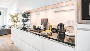 Eine moderne Küche mit weißen Schränken, einer schwarzen Arbeitsplatte und Edelstahlgeräten.