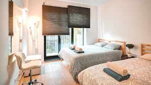 Ein modernes Schlafzimmer mit zwei Betten, einem Schreibtisch und einem Stuhl.