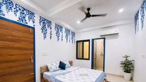 A bedroom with a bed, a ceiling fan, a potted plant, and a shower. - Hotel Radha Ratan Inn (Jaipur)