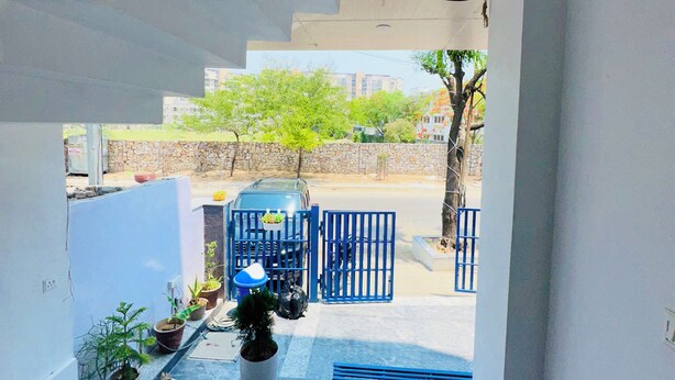 A staircase leading to a covered outdoor area with potted plants and a blue gate. - Hotel Radha Ratan Inn (Jaipur)