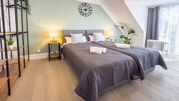 A modern bedroom with a large bed, two bedside tables, a wall clock, and a view of the outdoors.