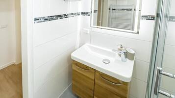 Un bany amb un lavabo blanc, un armari de fusta i un mirall.