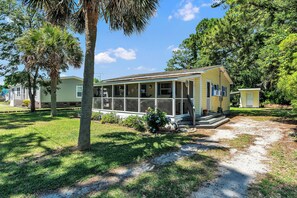 A charming single-story vacation rental framed by mature palms and lush landscaping, offering a peaceful retreat with a screened porch and private outdoor space. - Charming Fisherman’s Cottage - Walk to Bogue Sound | DOGS OK (Cape Carteret)