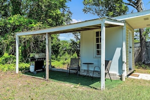 Your private outdoor lounge features a BBQ grill and shaded seating area, perfect for grilling and relaxing surrounded by lush greenery. - Charming Fisherman’s Cottage - Walk to Bogue Sound | DOGS OK (Cape Carteret)