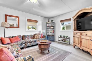 Settle into this cozy living room where colorful cushions and rustic wood accents create a warm, homey retreat perfect for unwinding after exploring the area. - Charming Fisherman’s Cottage - Walk to Bogue Sound | DOGS OK (Cape Carteret)