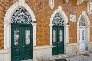 A row of green doors with intricate white designs, set against a patterned wall with visible house numbers 1669 and 1671.